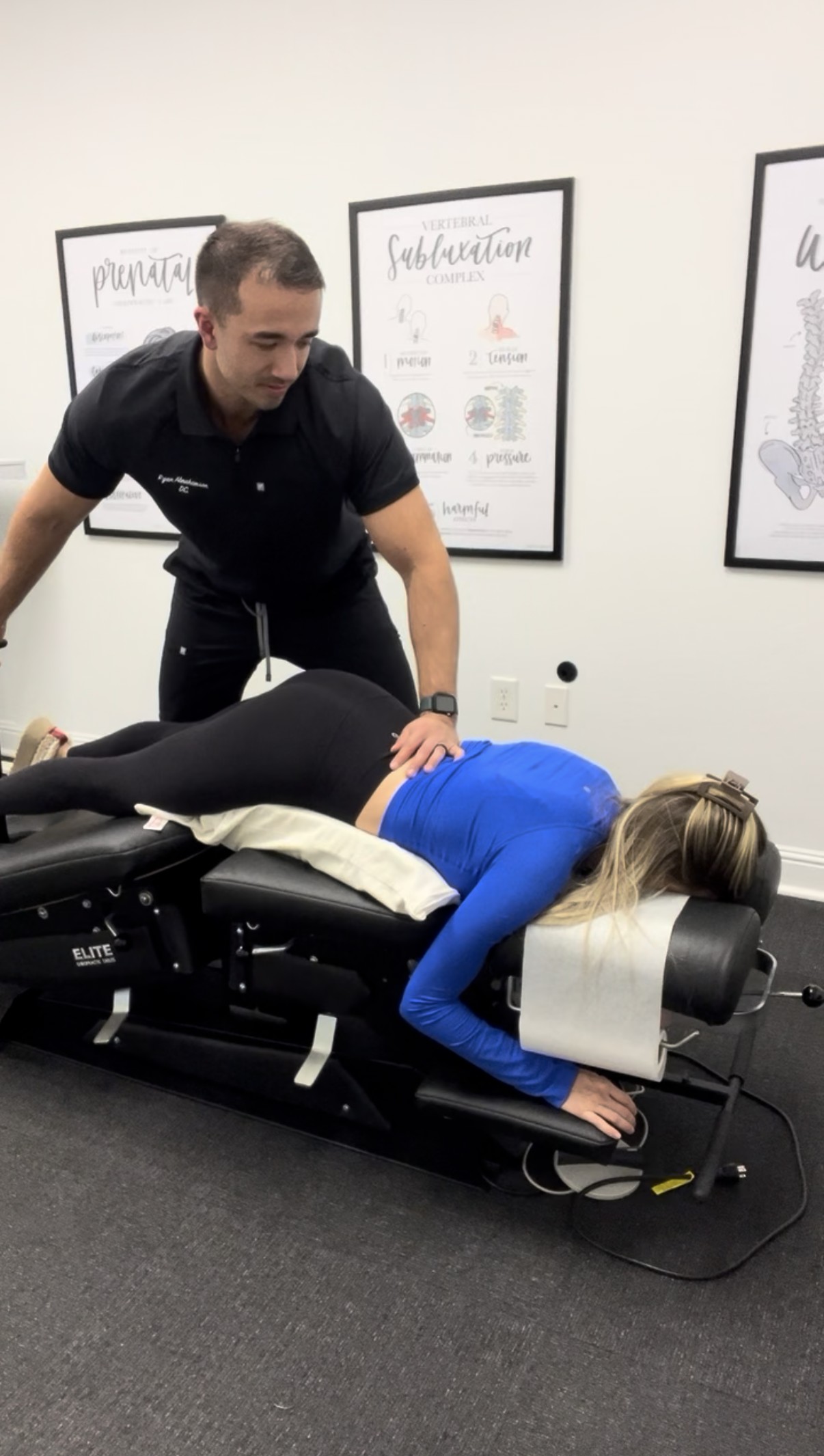 A chiropractor adjusts a patient lying face down on an examination table.